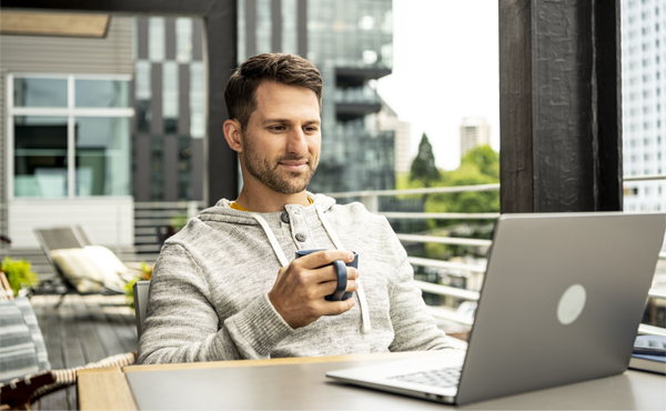 Man drinking coffee while working on laptop