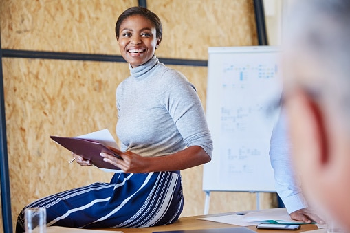 Lady sitting on desk with paperwork in hands