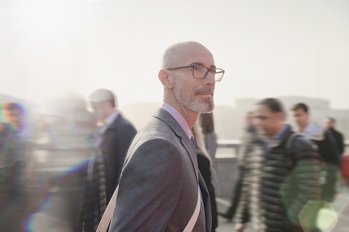 Man in suit and glasses standing in a crowd