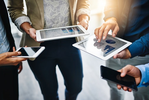 Four people holding devices out in a circle