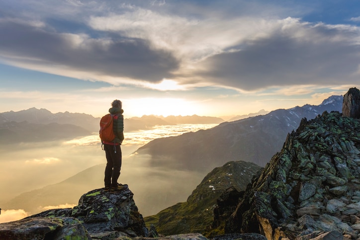 Man standing on top of mountain looking at sunrise