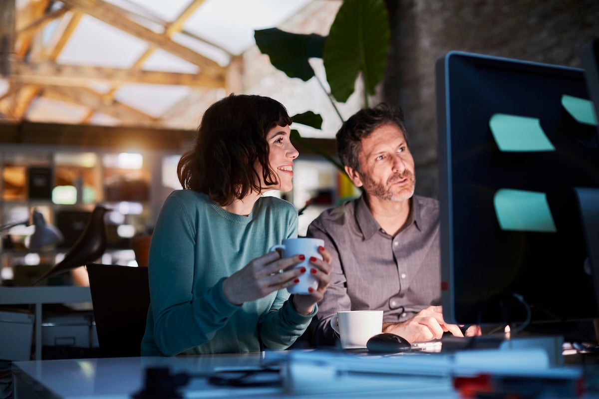 man and woman smiling at computer