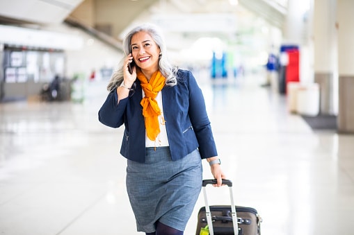Lady with orange scarf on walking through airport with suitcase