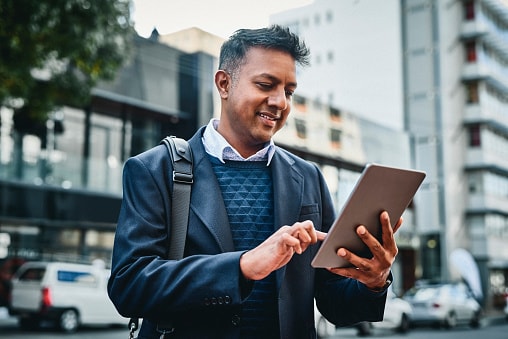 Man in street with rucksack on looking at tablet