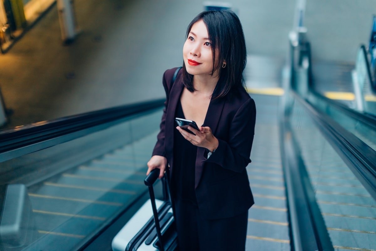 woman on phone on escalator at train station