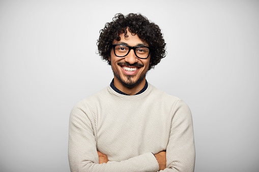 Man in white jumper standing with arms folded 