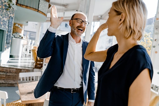 Man and women in office about to high five each other